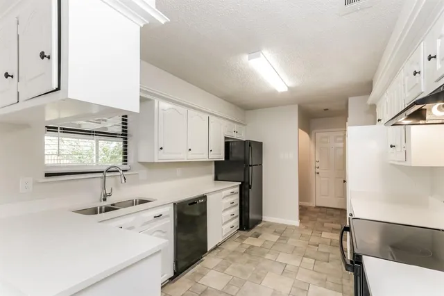 a kitchen with stainless steel appliances granite countertop a sink refrigerator and cabinets