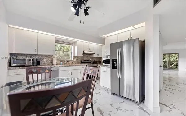 a kitchen with a refrigerator a stove a sink a dining table and chairs