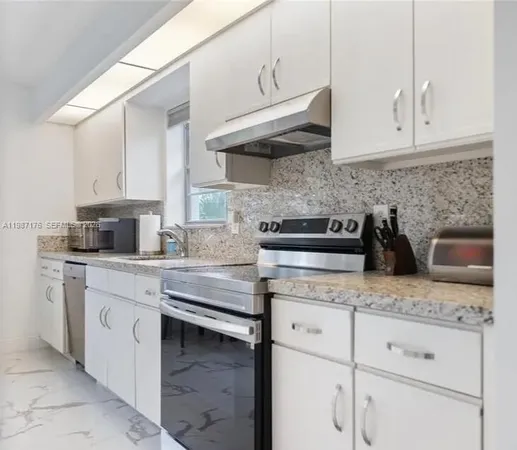 a kitchen with granite countertop white cabinets and a stove