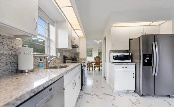 a kitchen with stainless steel appliances granite countertop a refrigerator a stove and a sink