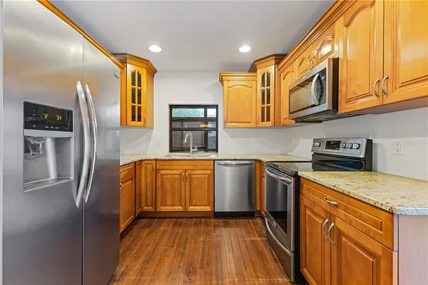 a kitchen with stainless steel appliances granite countertop a refrigerator a sink dishwasher and wooden cabinets with wooden floor