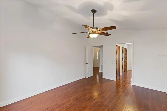 a view of an empty room with a chandelier fan and wooden floor