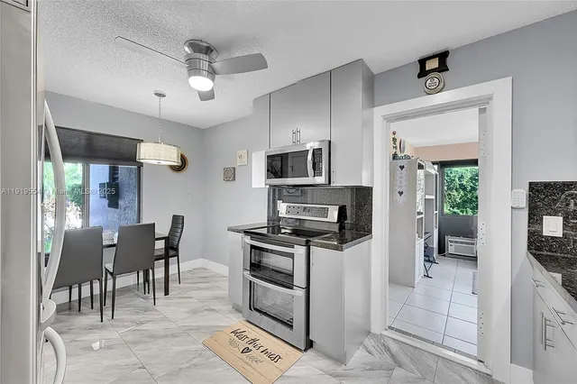 a kitchen with granite countertop a sink stainless steel appliances and white cabinets