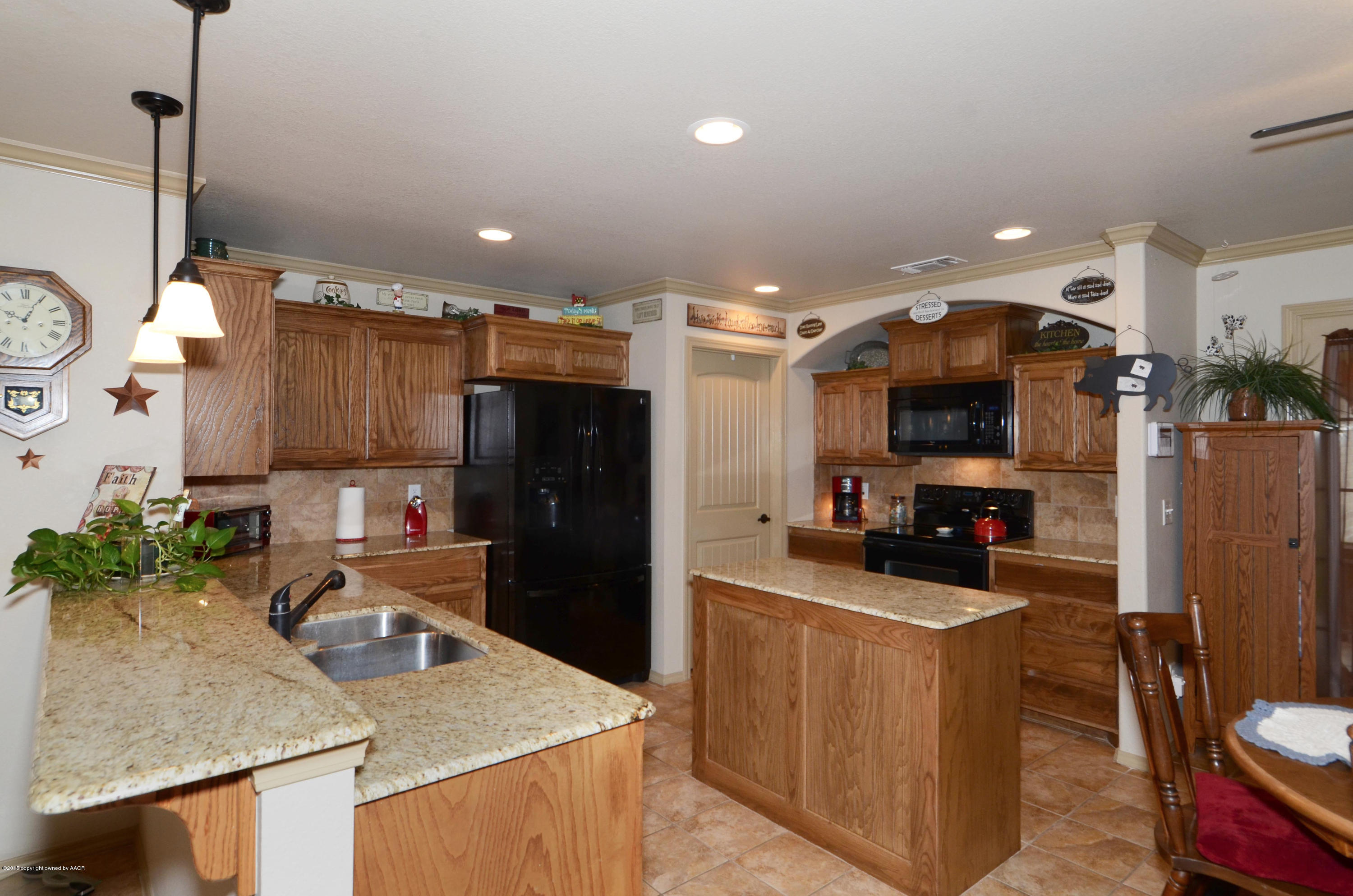 3705 Arden Road Amarillo, TX 79118 - Photo 4 of 20 a kitchen with granite countertop a refrigerator a stove a sink a dining table and chairs with wooden floor