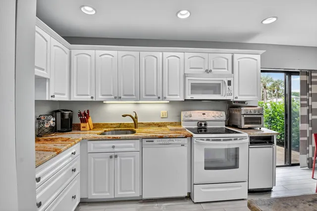 a kitchen with stainless steel appliances granite countertop a refrigerator sink and white cabinets