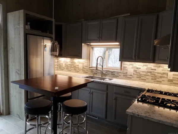 a kitchen with stainless steel appliances a table chairs and a refrigerator