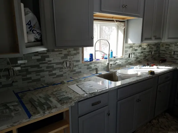 a kitchen with granite countertop a sink a stove and cabinets