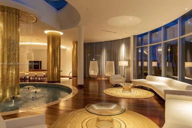 a living room with couches a fireplace with kitchen view