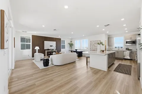 a large white kitchen with wooden floor and a large window