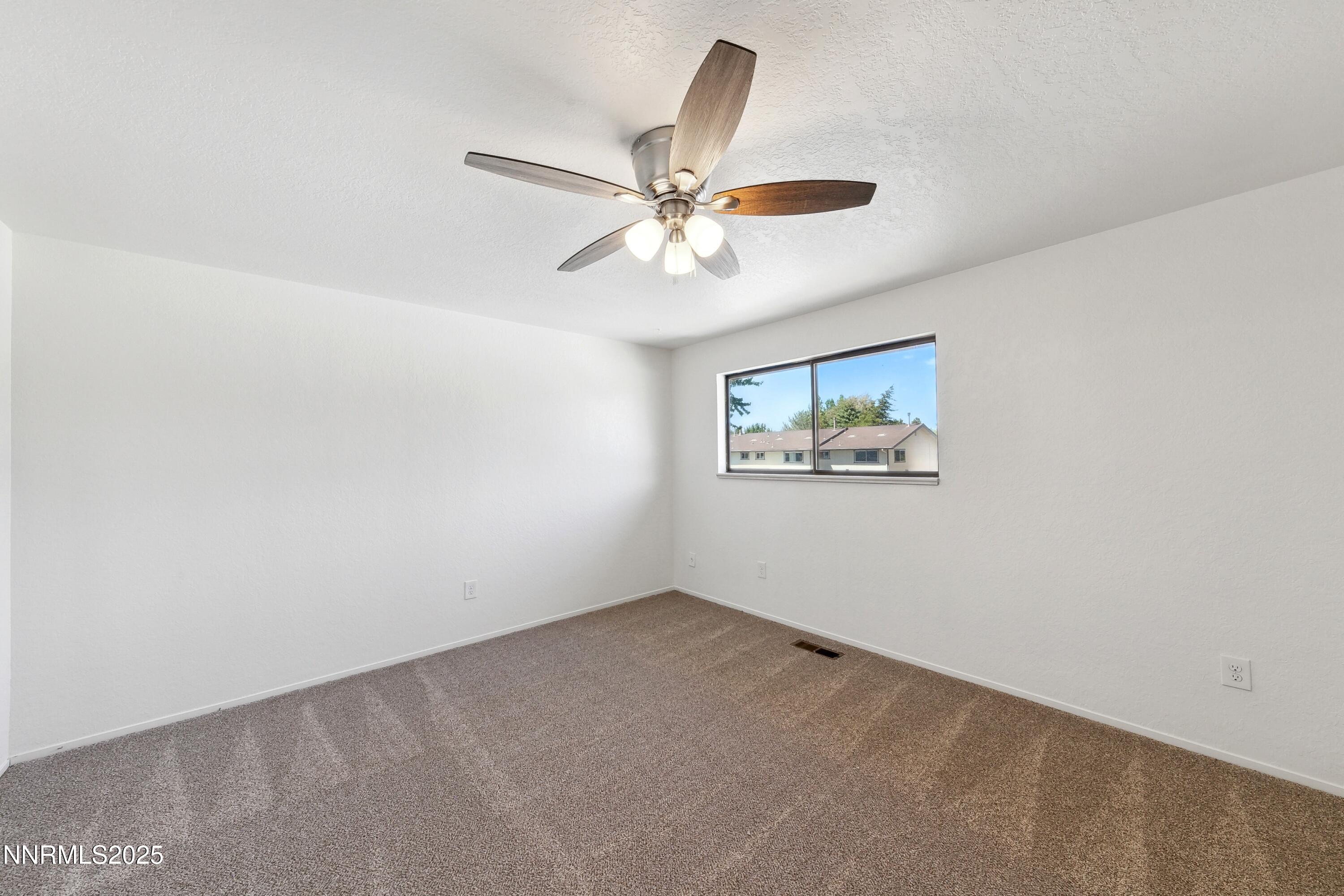 718 Travis Drive, Unit D Carson City, NV 89701 - Photo 14 of 19 an empty room with a window and a fan
