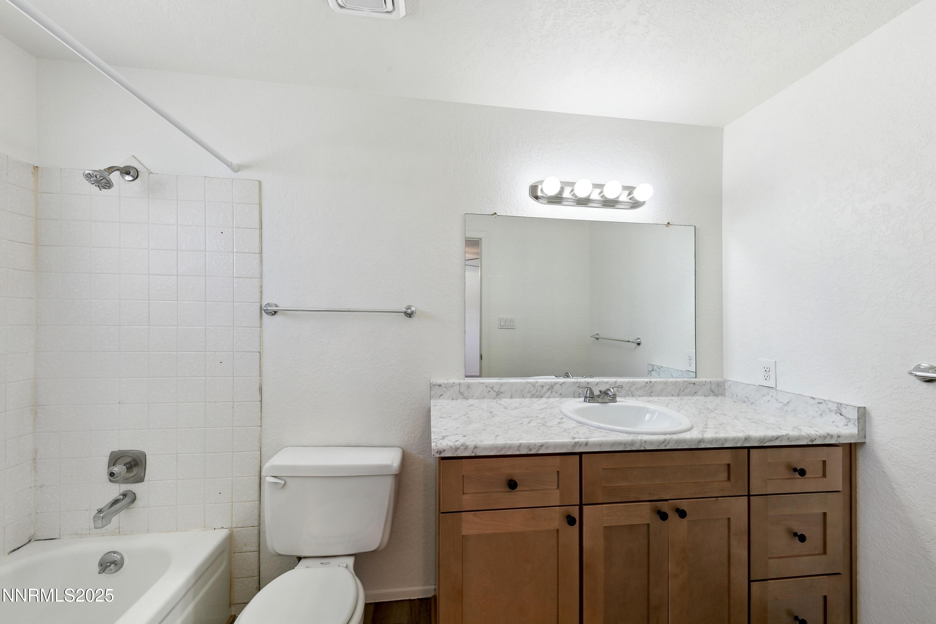 718 Travis Drive, Unit D Carson City, NV 89701 - Photo 15 of 19 a bathroom with a granite countertop sink toilet a large mirror and shower