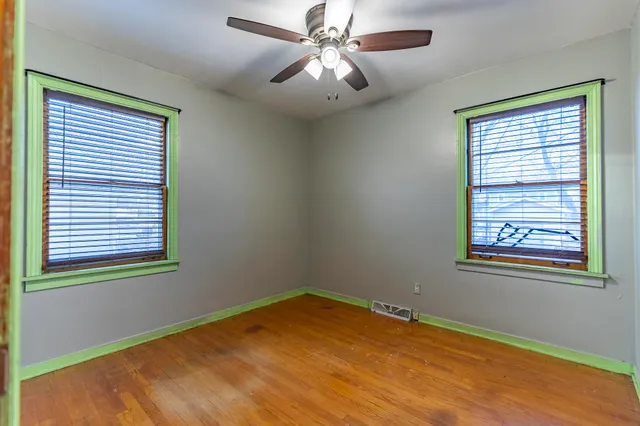 a view of an empty room with a window and wooden floor