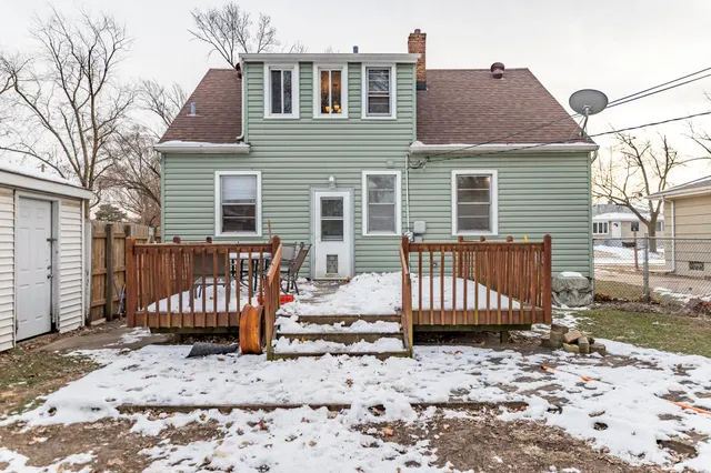 a view of a house with a wooden bench in a backyard