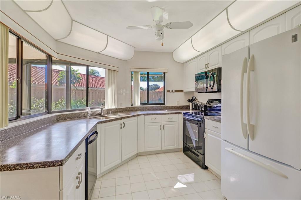 805 Reef Point Circle Naples, FL 34108 - Photo 13 of 33 a large kitchen with kitchen island granite countertop a sink window and cabinets