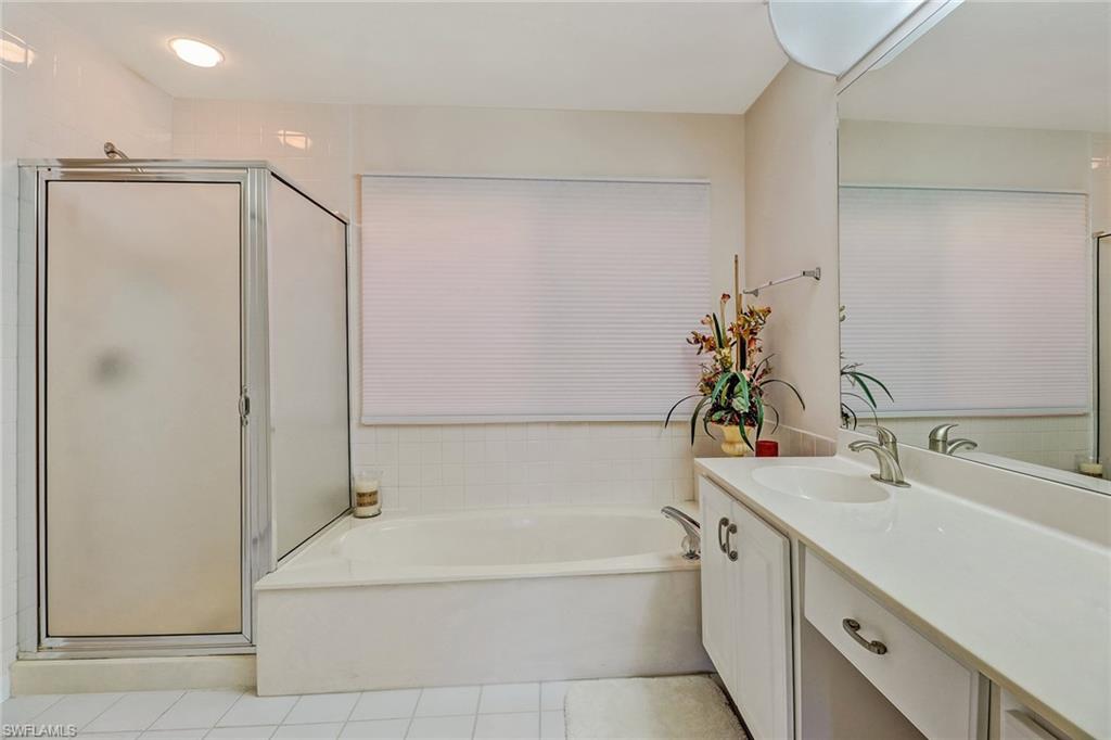 805 Reef Point Circle Naples, FL 34108 - Photo 25 of 33 a bathroom with a bathtub sink vanity and mirror
