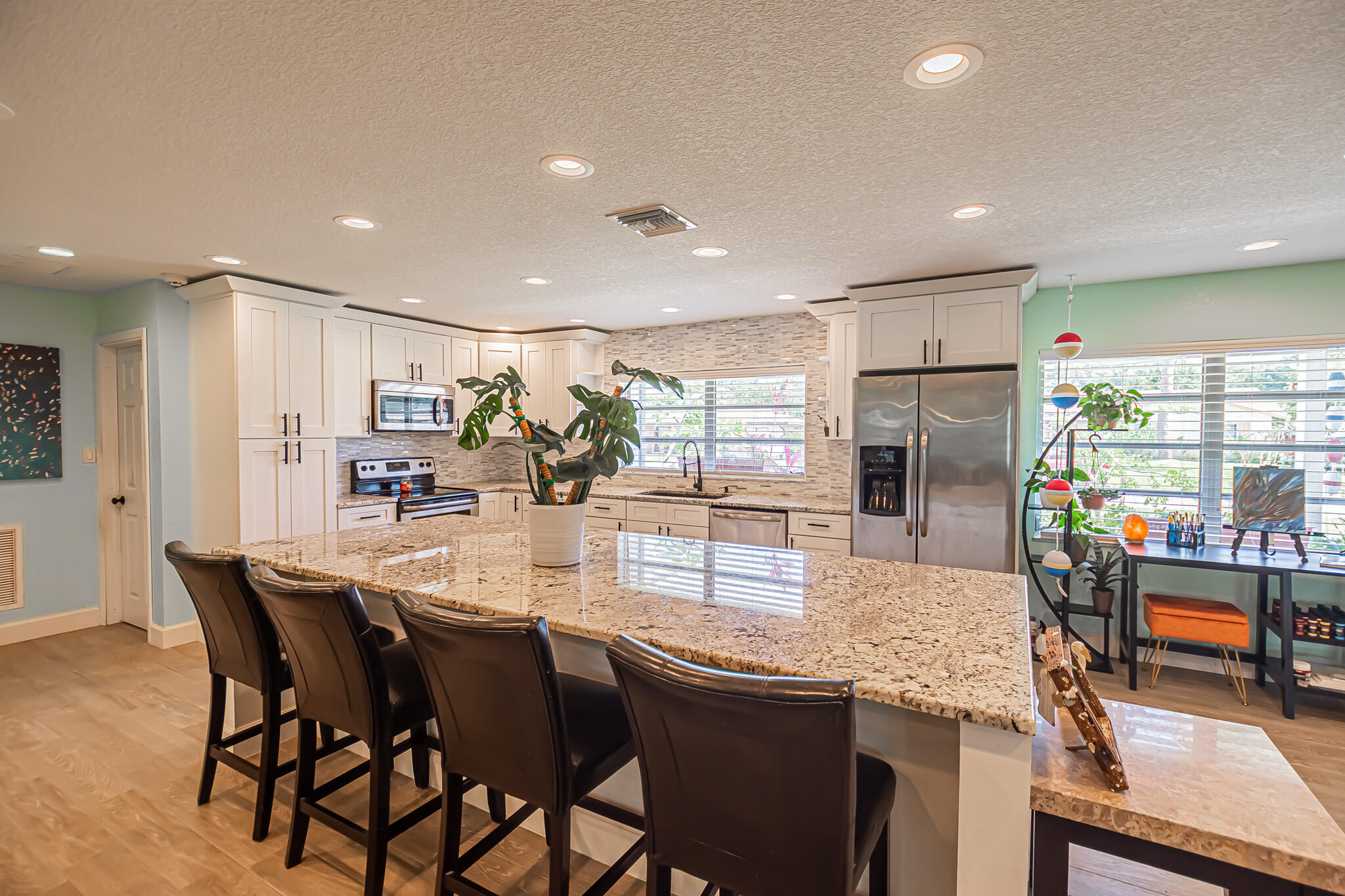 a dining hall with stainless steel appliances granite countertop a dining table chairs and couches