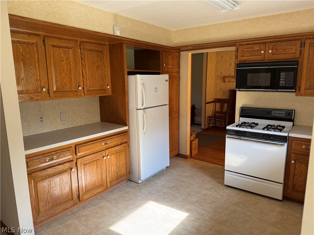 5920 Weaver Road New Franklin, OH 44216 - Photo 5 of 24 Kitchen featuring wood cabinetry, light-toned countertops, tile flooring, and white appliances including a refrigerator and gas range
