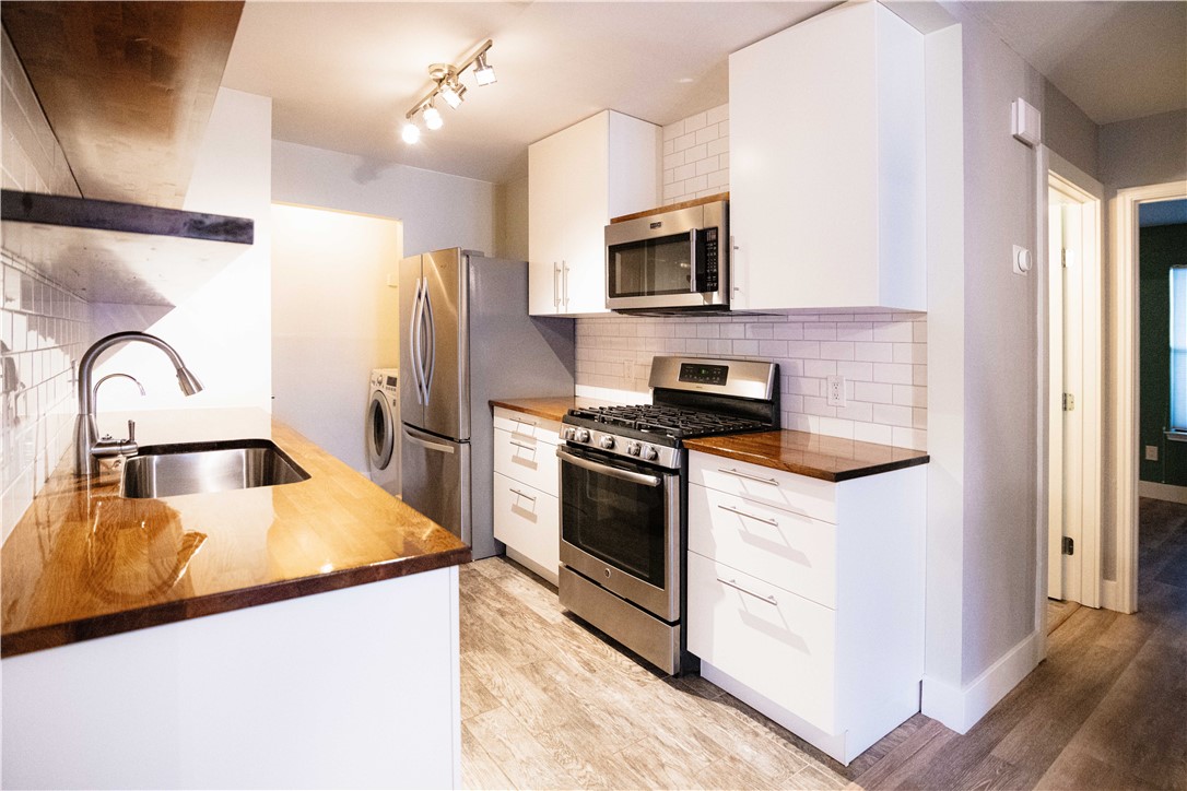 a kitchen with stainless steel appliances white cabinets a sink and a stove