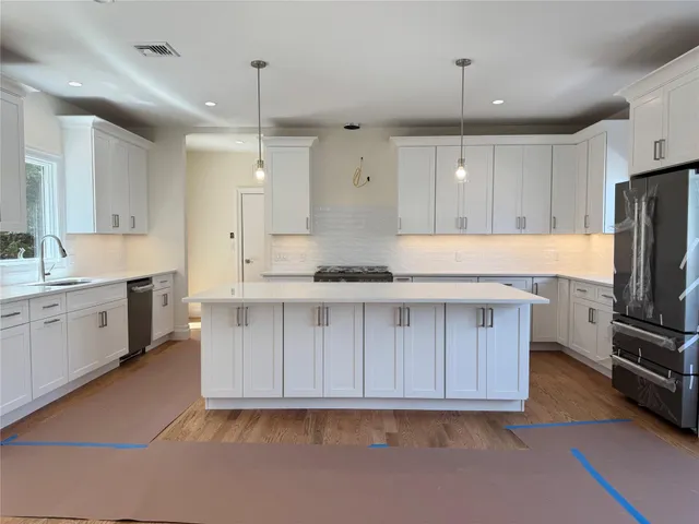 a large kitchen with cabinets stove a sink and a refrigerator