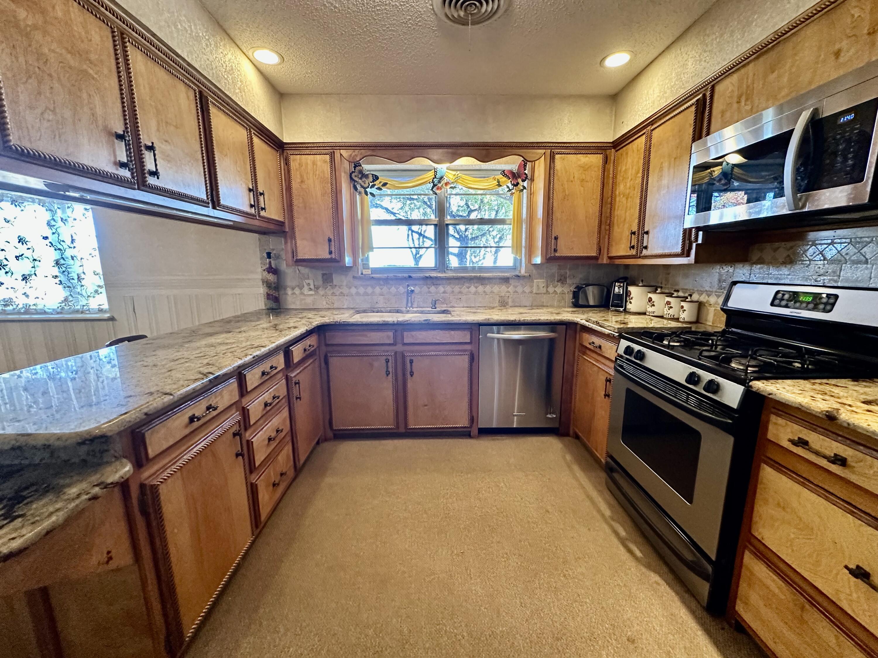 7844 Fm 1318 Tulia, TX 79088 - Photo 22 of 42 a kitchen with stainless steel appliances granite countertop stove top oven a sink dishwasher and cabinets with wooden floor