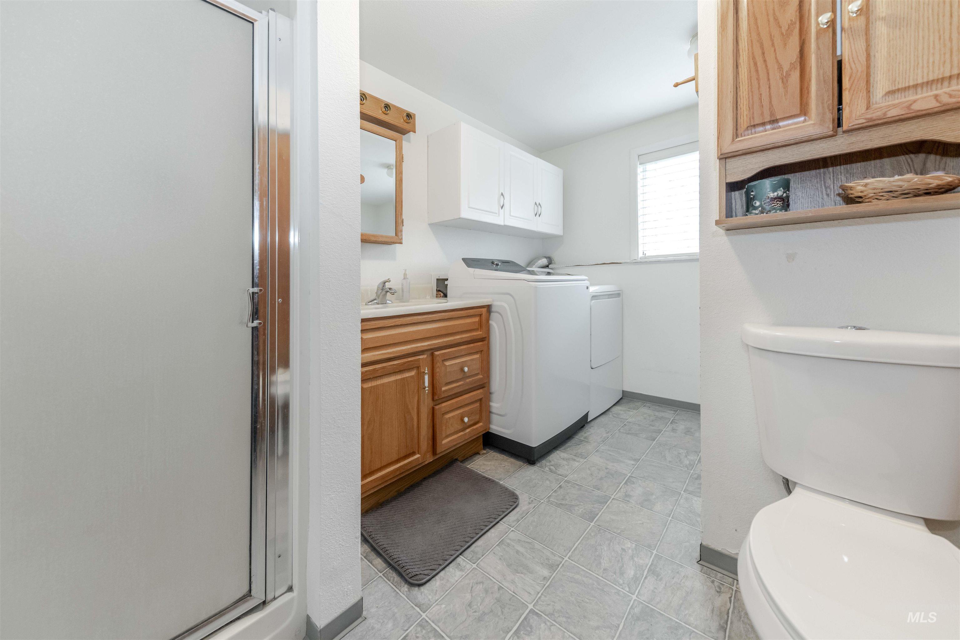 930 Preston Avenue Lewiston, ID 83501 - Photo 22 of 32 Full bath featuring washing machine and clothes dryer, a shower stall, and vanity