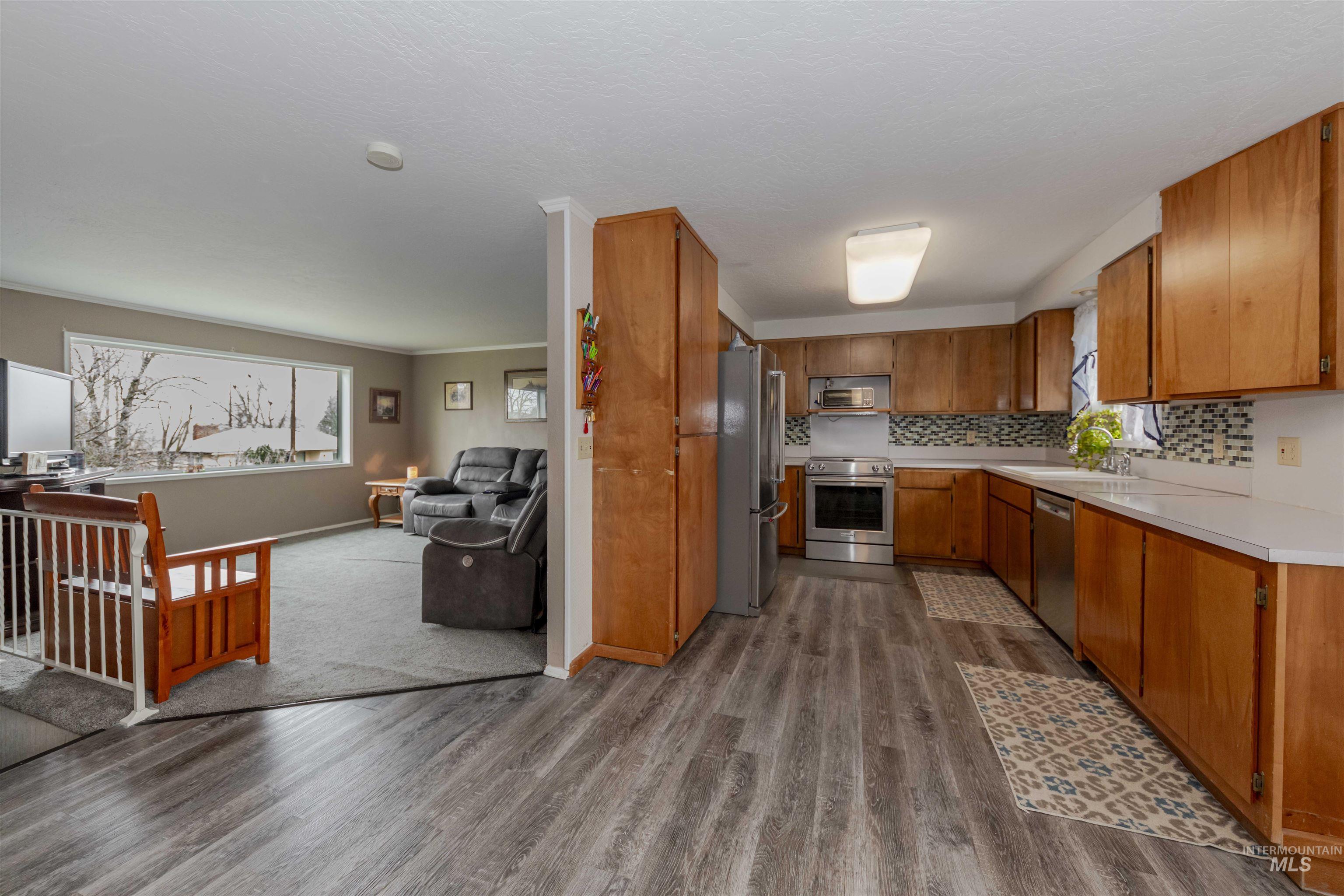 930 Preston Avenue Lewiston, ID 83501 - Photo 32 of 32 Kitchen featuring appliances with stainless steel finishes, light countertops, brown cabinets, dark wood-style flooring, and open floor plan