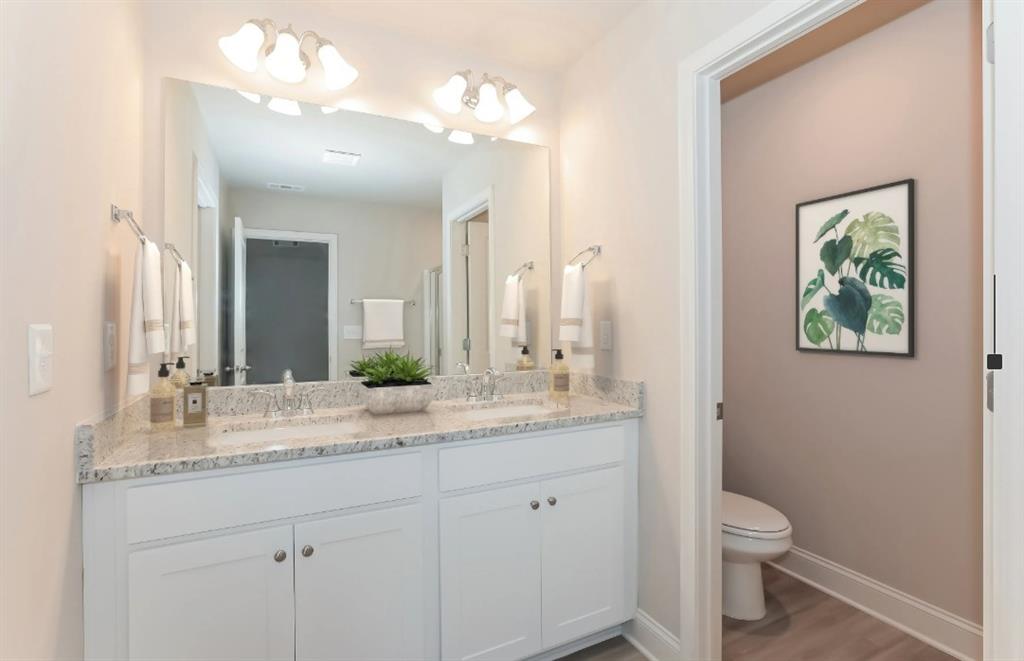 2150 Spring Rush Drive, Unit 127 Buford, GA 30519 - Photo 9 of 15 a bathroom with a granite countertop sink a toilet and a mirror