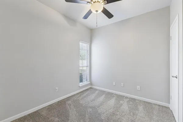 an empty room with a chandelier fan and windows