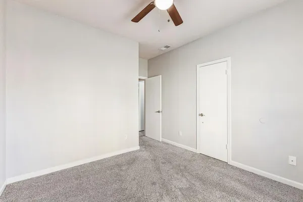 an empty room with ceiling fan and window