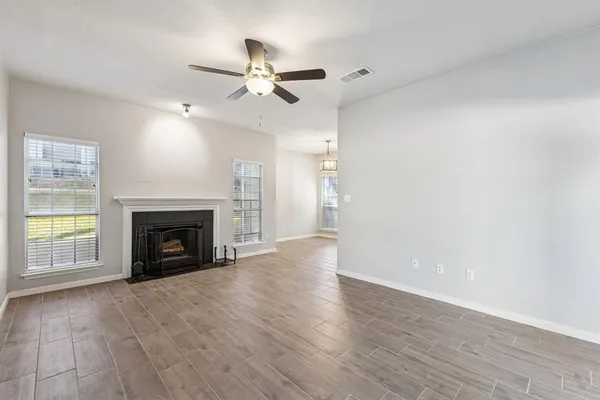 a view of an empty room with wooden floor fireplace and a window