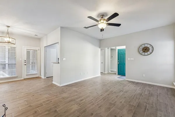 a view of an empty room with wooden floor and a ceiling fan