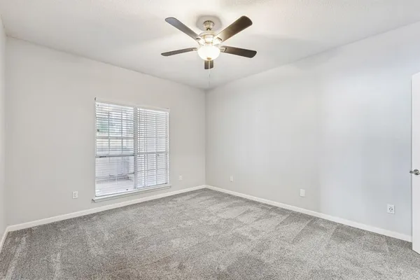 an empty room with chandelier fan and windows