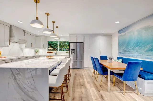 a kitchen with stainless steel appliances kitchen island granite countertop a dining table chairs and a refrigerator