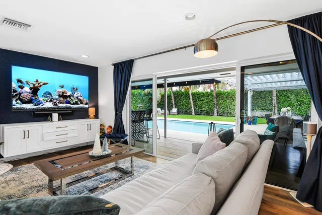 a living room with furniture a flat screen tv and floor to ceiling window