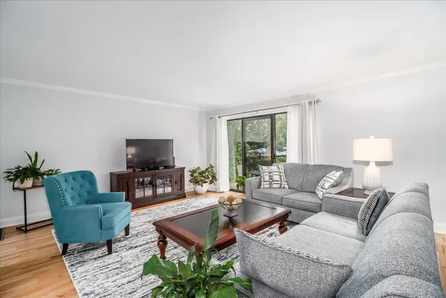 a living room with furniture a flat screen tv and a large window