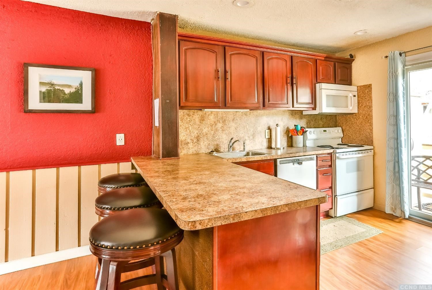 13 Scribner Hollow Road, Unit B1 Hunter, NY 12442 - Photo 12 of 37 a kitchen with stainless steel appliances kitchen island granite countertop wooden cabinets a dining table and chairs