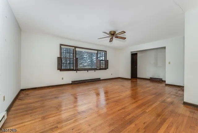 a view of an empty room with a window and wooden floor