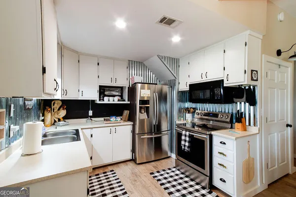 a kitchen with stainless steel appliances a refrigerator stove and white cabinets