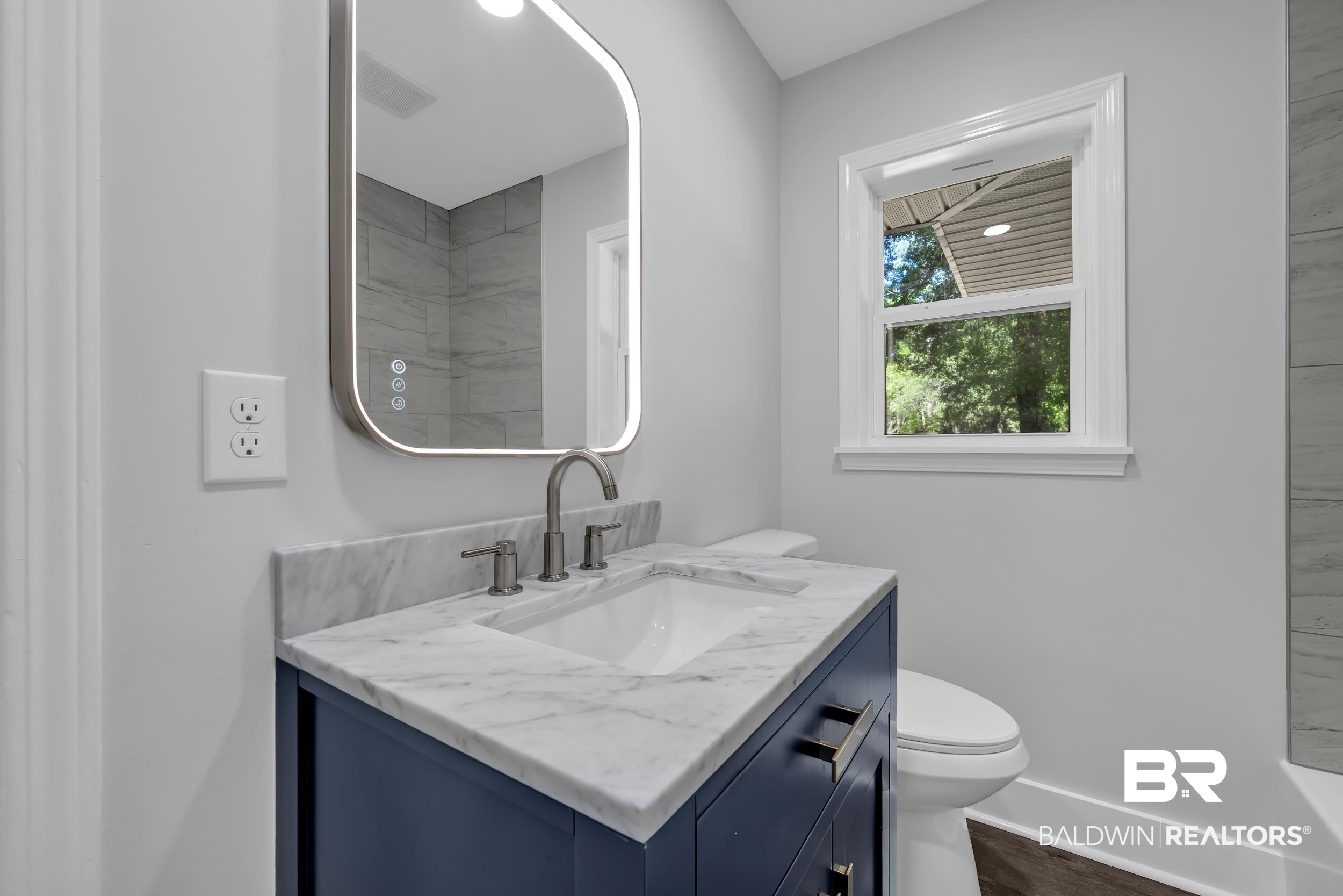 2712 Shelton Beach Rd Extension Mobile, AL 36613 - Photo 18 of 24 Vanity featuring a white undermount sink, a stone countertop with gray veining, and a navy blue cabinet with dark hardware