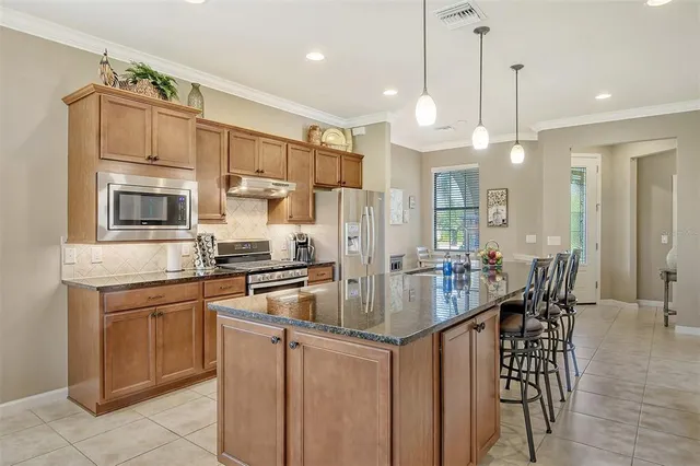a kitchen with stainless steel appliances granite countertop a sink a stove a dining table and chairs