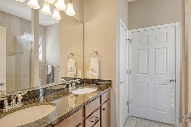 a bathroom with a granite countertop double vanity sink and a mirror
