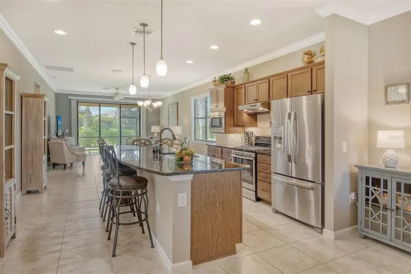a kitchen with stainless steel appliances a refrigerator oven a kitchen island a table and chairs