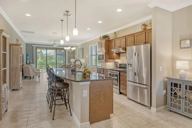 a kitchen with stainless steel appliances a refrigerator oven a kitchen island a table and chairs