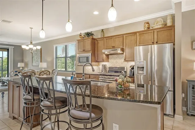 a kitchen with stainless steel appliances a dining table chairs and chandelier