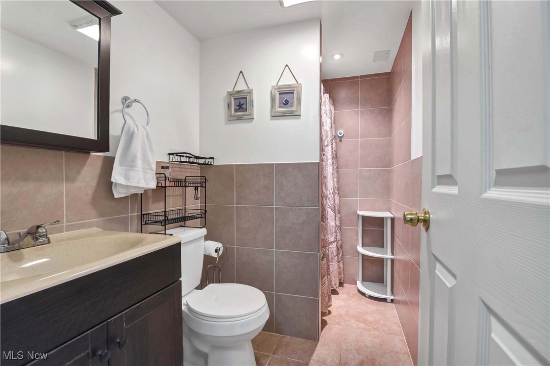 9999 Reichert Road Parma, OH 44130 - Photo 33 of 44 Full bath featuring a shower with curtain, vanity, light tile patterned flooring, recessed lighting, and tile walls