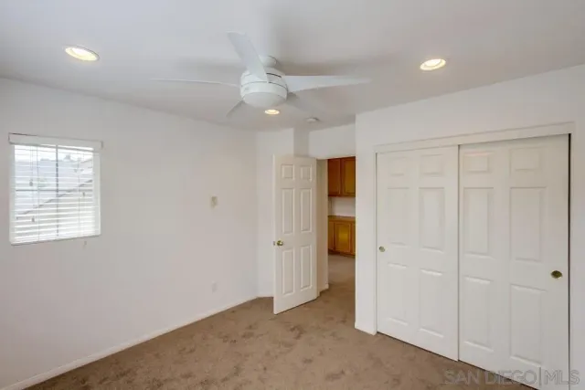 an empty room with closet and a ceiling fan