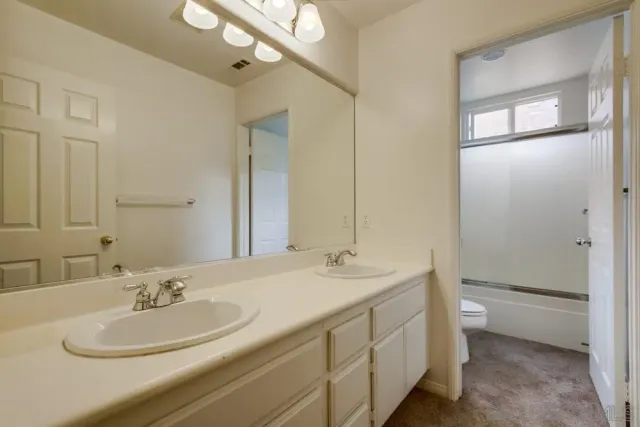 a bathroom with a double vanity sink toilet and a mirror