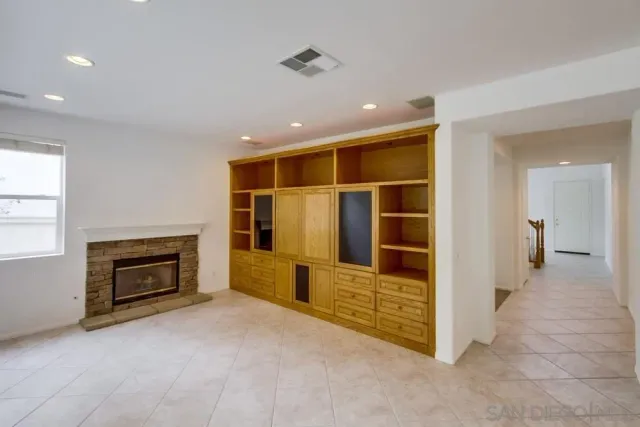 a view of an empty room with a fireplace and a cabinet
