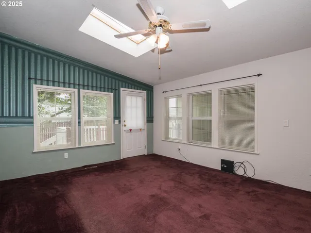 an empty room with fan and windows