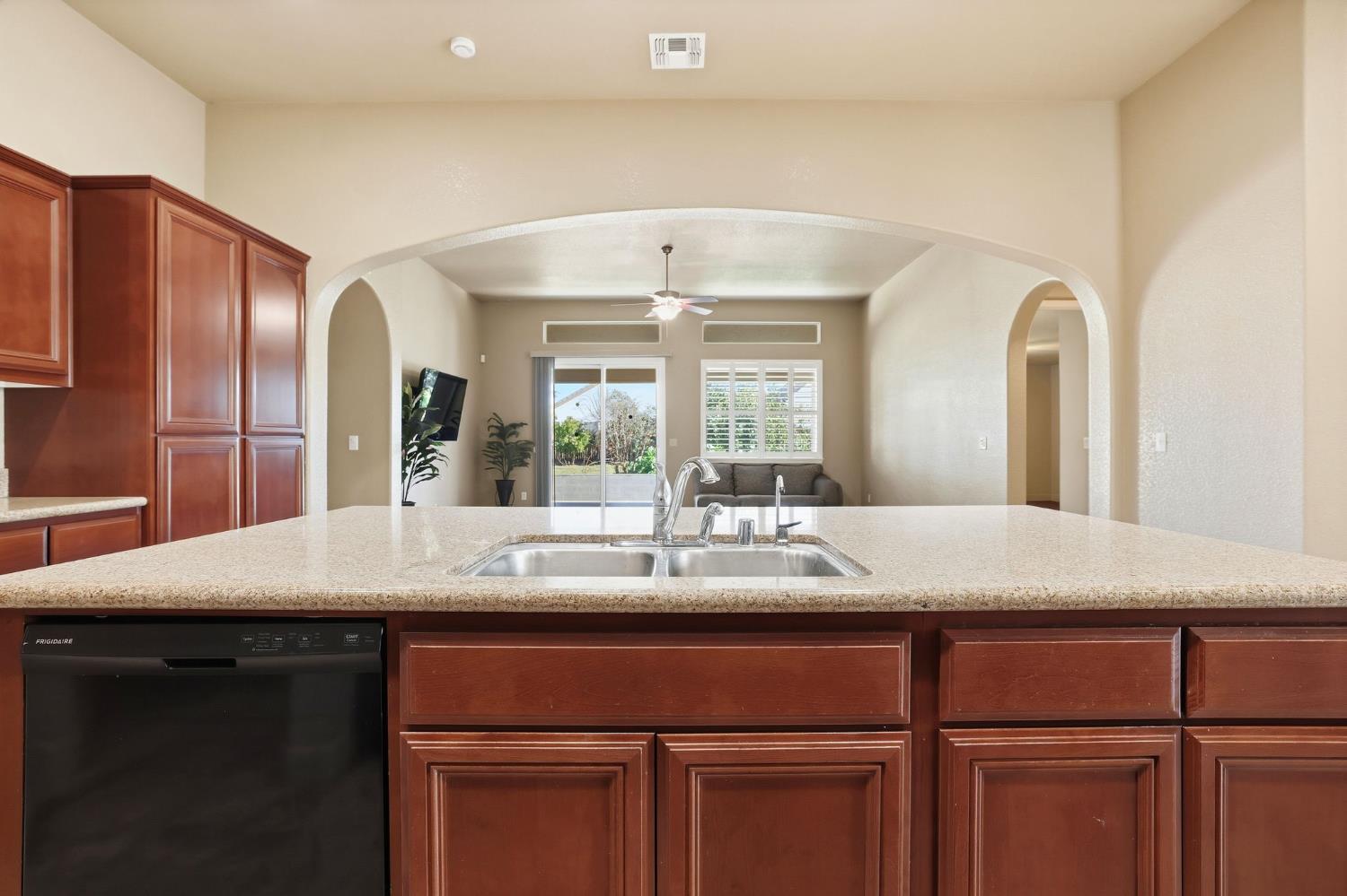 1730 Tasca Lane Manteca, CA 95337 - Photo 83 of 83 kitchen : arched walkways, dishwasher, open floor plan, brown cabinetry, and a kitchen island with sink